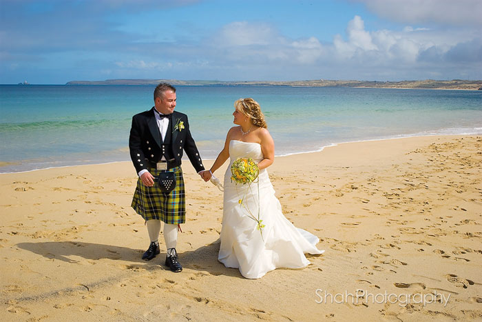 After their wedding ceremony, bride and groom, photographed walking along Carbis bay beach