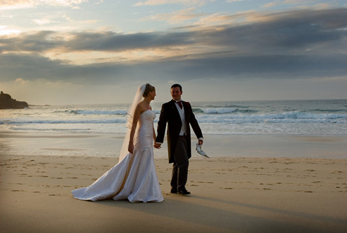 bride and groom stroll along a beach at St Ives