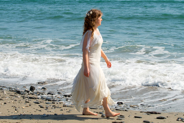 reportage bridal beach wedding photograph as bride strolls along the Cornish beach