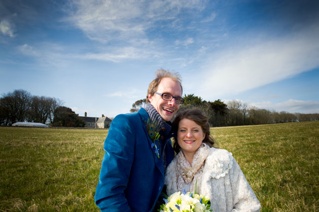 Bride and groom with wedding venue in background