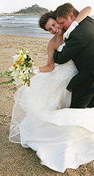 Janine and Jonathan the bride and groom photographed having a cuddle on Marazion beach with St Michael's Mount in the background