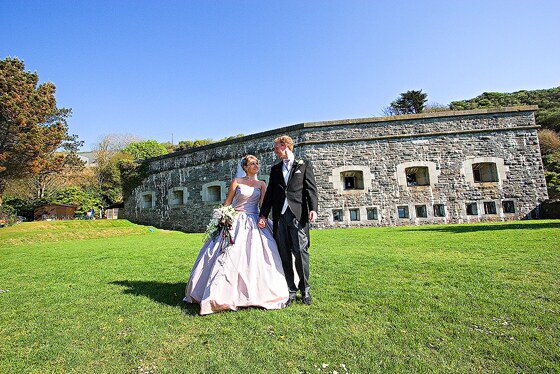 The bride and groom with Polhawn Fort in the background