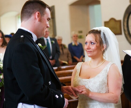 wedding ceremony photograph of the bride putting the groom's wedding ring on