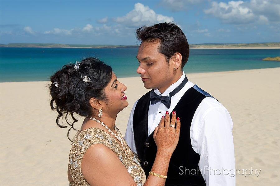 The bride and groom close up against a backdrop of Porthminster beach and St Ives bay in sunshine