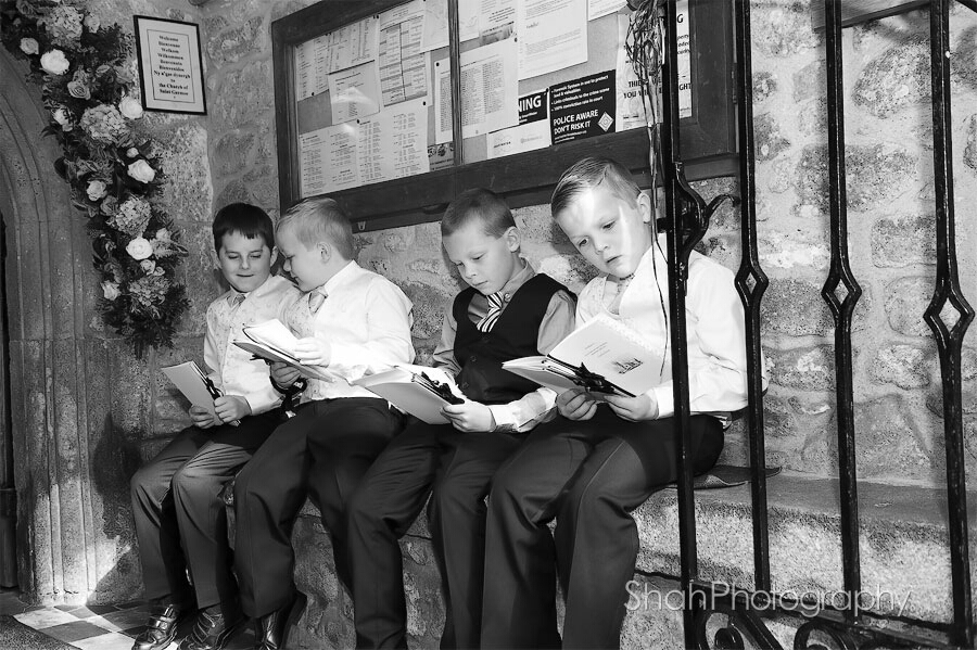 page boys studying the order of service sitting at the entrance to the church before the wedding ceremony a black and white photograph