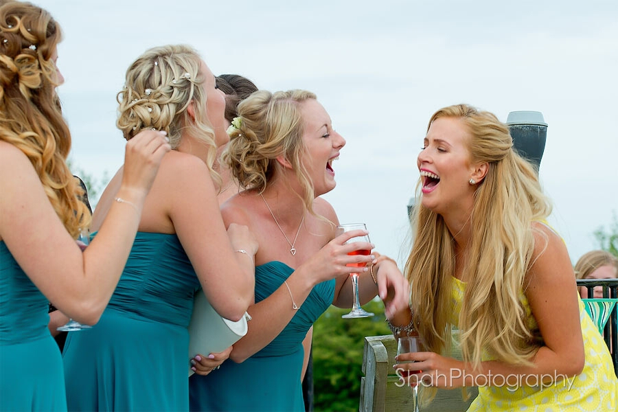 Laughing bridesmaids and a wedding guest share a hilarious moment during the pre reception drinks at this wedding in Devon