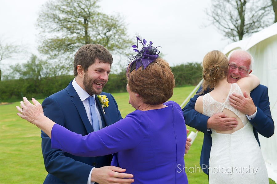 Emotional groom hugs his mother in law while the bride hugs her father after the wedding ceremony. Love and happiness in abundance.