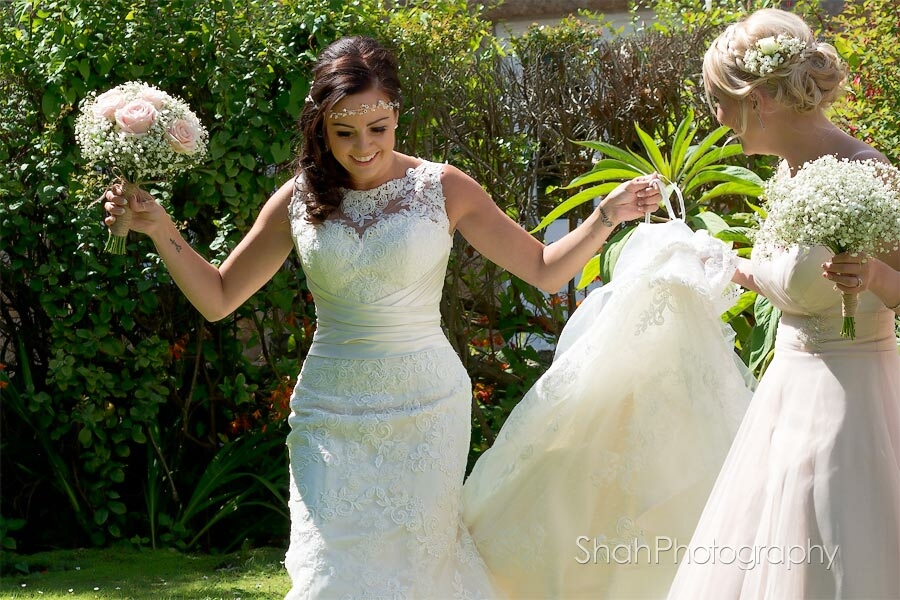 Bride on her way to her wedding ceremony with her bridesmaid who holds the wedding dress